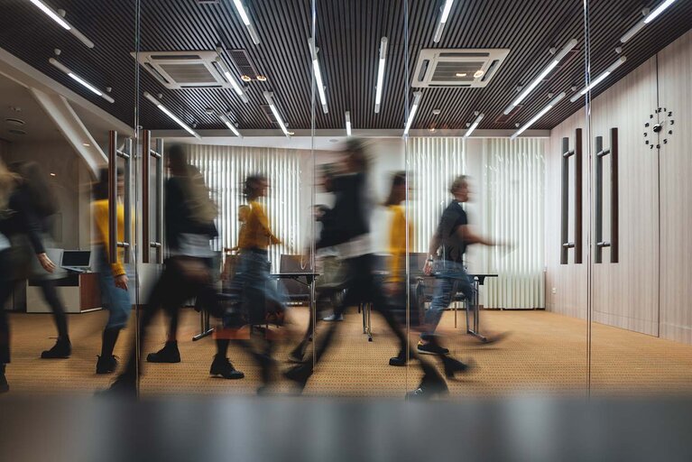 Eine Gruppe von Geschäftsleuten, die durch einen modernen, offenen Raum gehen. Ein Team von Büroangestellten in einem Coworking-Center. Bewegungsunschärfe. Konzeptarbeit in Arbeit