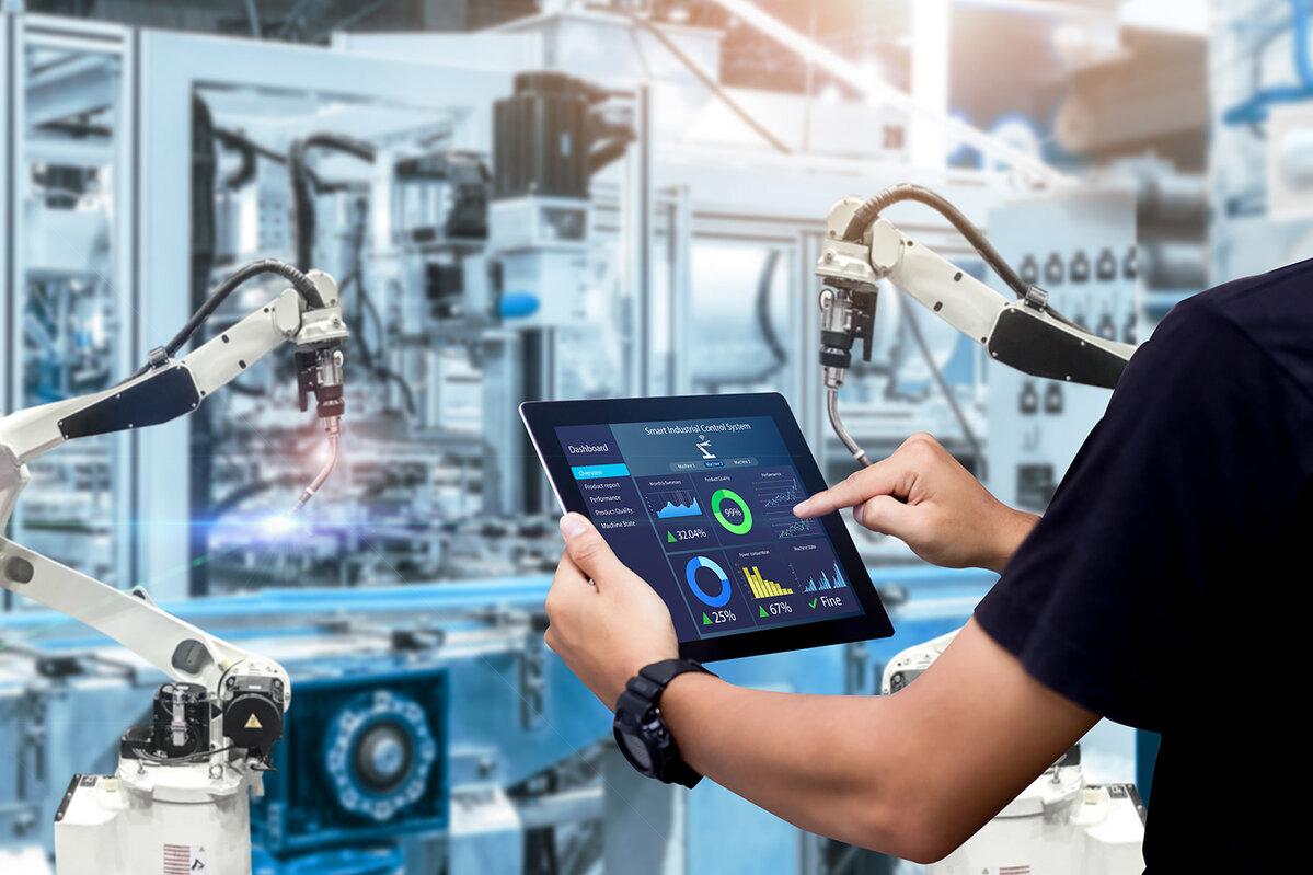  Intelligentes Steuerungskonzept für die Industrie. Hände, die ein Tablet halten, vor dem Hintergrund einer verschwommenen Automatisierungsmaschine 