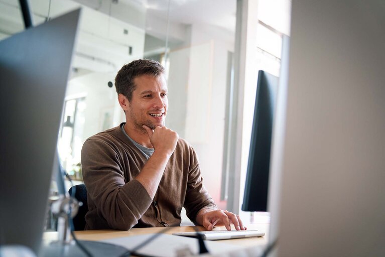 Programmierer, Webentwickler und Designer, die im Büro arbeiten und die mobilen und Desktop-Versionen von Websites vergleichen 