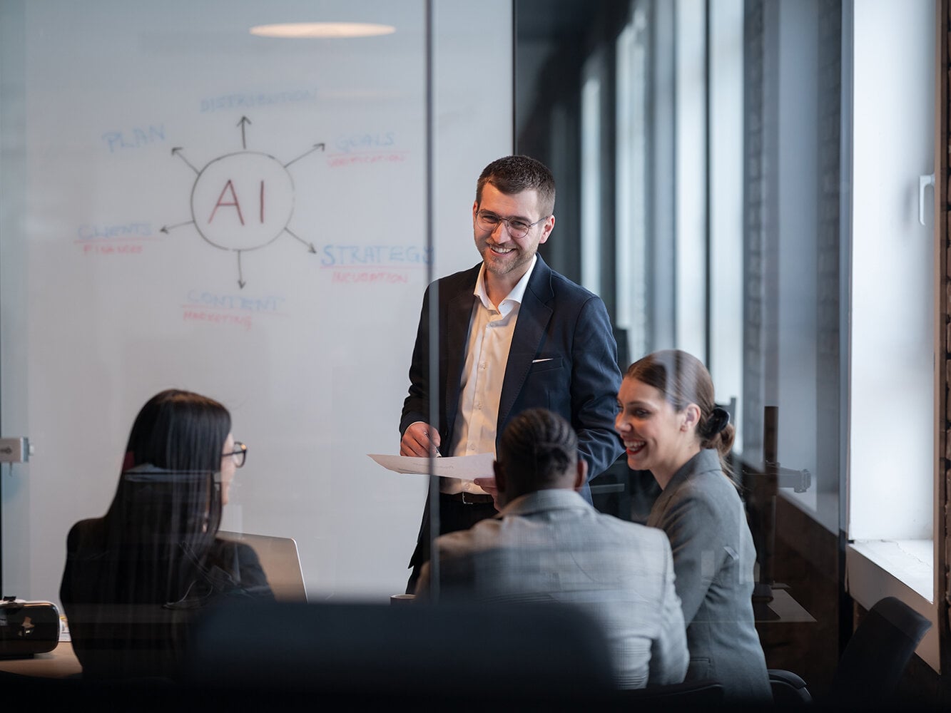 Ein vielfältiges Geschäftsteam in einem modernen Büro während einer Besprechung, bei der die Strategie im Bereich künstliche Intelligenz erörtert wird. Konzept der KI-Innovation, Teamarbeit, Führung, Unternehmensplanung, professionelle Zusammenarbeit
