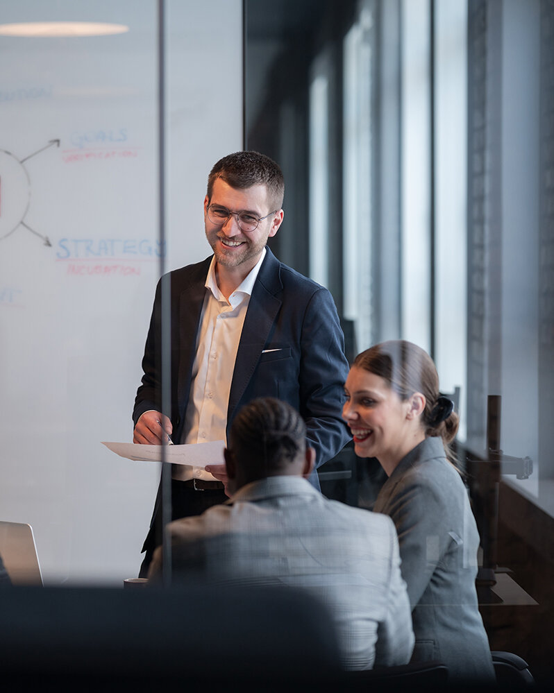 Ein vielfältiges Geschäftsteam in einem modernen Büro während einer Besprechung, bei der die Strategie im Bereich künstliche Intelligenz erörtert wird. Konzept der KI-Innovation, Teamarbeit, Führung, Unternehmensplanung, professionelle Zusammenarbeit