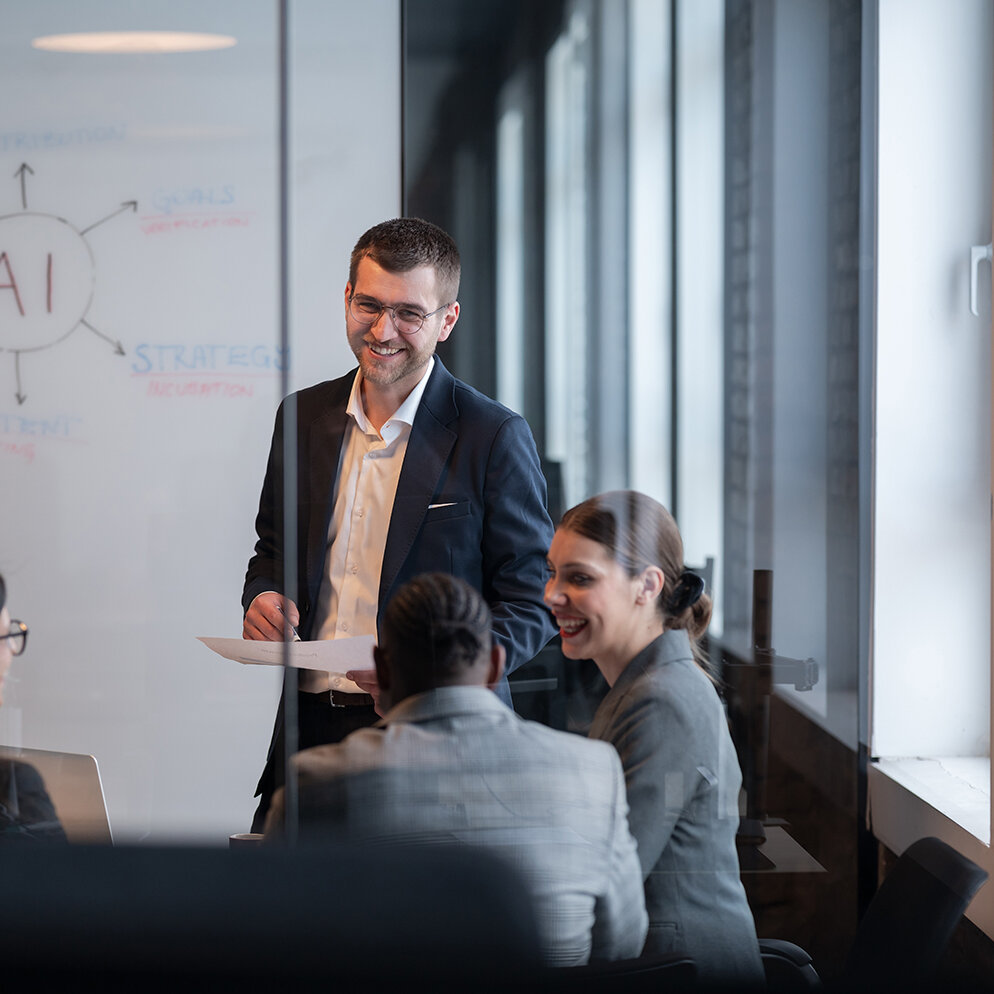 Ein vielfältiges Geschäftsteam in einem modernen Büro während einer Besprechung, bei der die Strategie im Bereich künstliche Intelligenz erörtert wird. Konzept der KI-Innovation, Teamarbeit, Führung, Unternehmensplanung, professionelle Zusammenarbeit