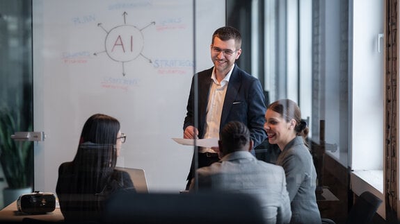 Ein vielfältiges Geschäftsteam in einem modernen Büro während einer Besprechung, bei der die Strategie im Bereich künstliche Intelligenz erörtert wird. Konzept der KI-Innovation, Teamarbeit, Führung, Unternehmensplanung, professionelle Zusammenarbeit