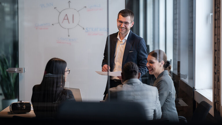 Ein vielfältiges Geschäftsteam in einem modernen Büro während einer Besprechung, bei der die Strategie im Bereich künstliche Intelligenz erörtert wird. Konzept der KI-Innovation, Teamarbeit, Führung, Unternehmensplanung, professionelle Zusammenarbeit