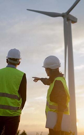 Ingenieure überprüfen den Betrieb eines Windkraftwerks, besprechen bei Sonnenuntergang die Strategie für ein Projekt im Bereich erneuerbare Energien und gestalten so eine nachhaltige Zukunft