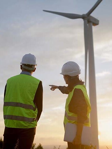 Ingenieure überprüfen den Betrieb eines Windkraftwerks, besprechen bei Sonnenuntergang die Strategie für ein Projekt im Bereich erneuerbare Energien und gestalten so eine nachhaltige Zukunft