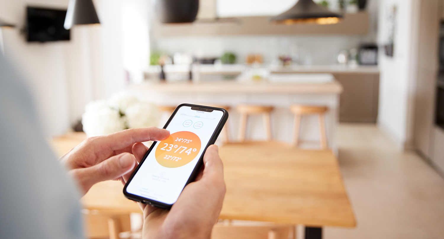Mann mit App auf Smart Phone steuert seine Zentralheizung