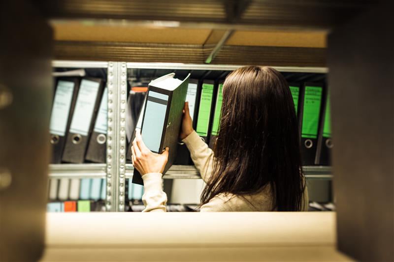 Junge Frau, die im Archiv Dokumente durchsieht 