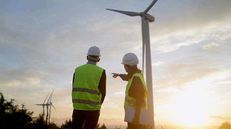 Ingenieure überprüfen den Betrieb eines Windkraftwerks, besprechen bei Sonnenuntergang die Strategie für ein Projekt im Bereich erneuerbare Energien und gestalten so eine nachhaltige Zukunft