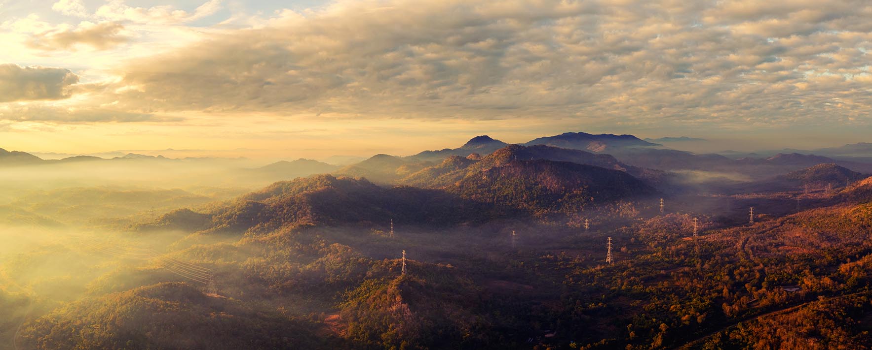 Luftaufnahme: Panorama eines malerischen Morgenbildes in den hohen Bergen mit Strommast in Pang Puay, Mae Moh, Lampang, Thailand. Ein wunderschöner Morgen mit goldenem Sonnenaufgang und wogendem Nebel.